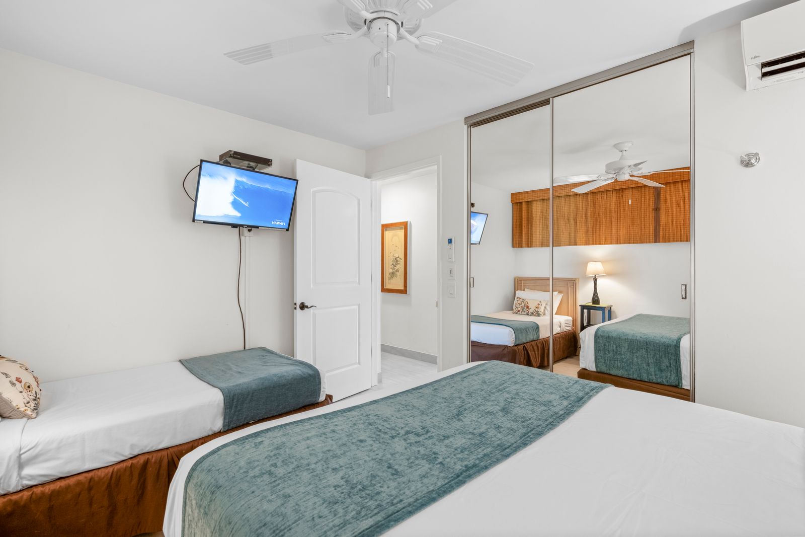 Wake up to a bright, airy bedroom designed for your comfort—two cozy beds, a ceiling fan, AC to keep you cool, a flat-screen TV for downtime, and spacious mirrored closets reflecting warmth and style throughout your stay.