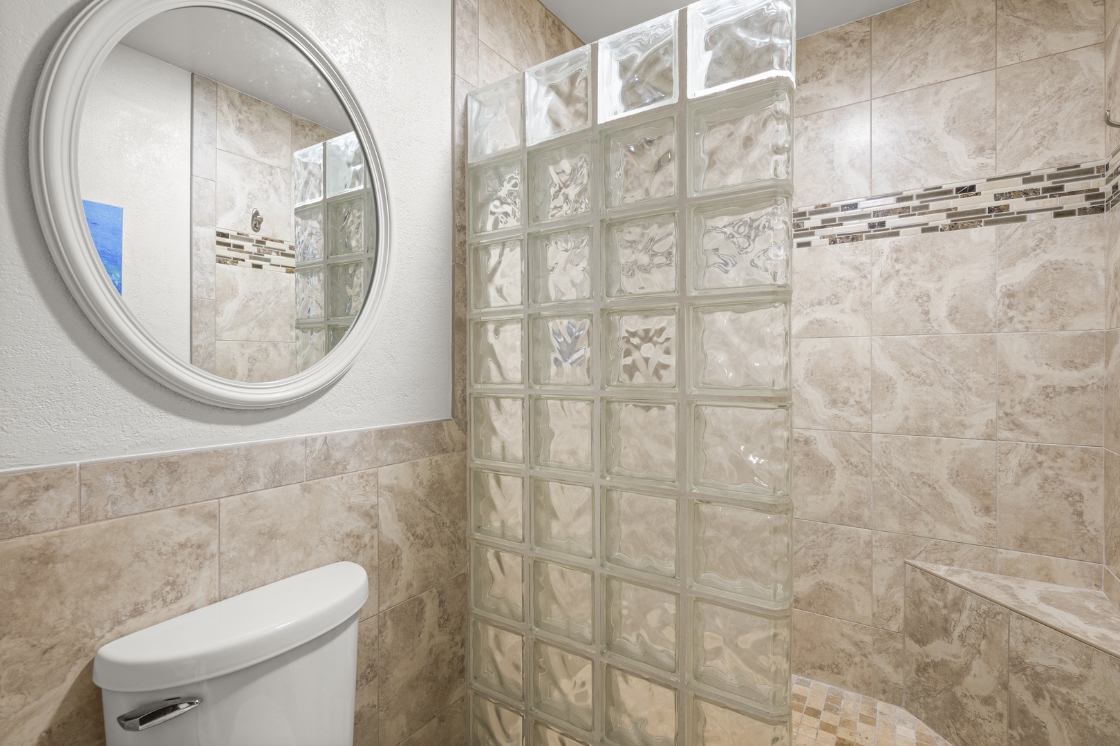 Your private bathroom features elegant glass block detailing, warm travertine tile, and a spacious walk-in shower designed for comfort and style.