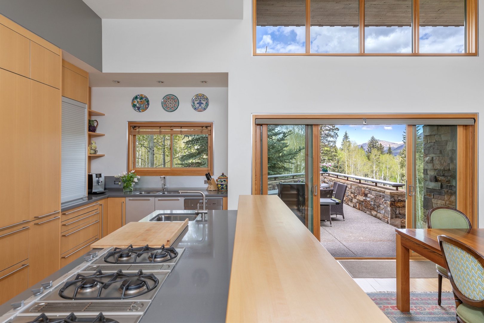 Kitchen and dining open to exterior deck with dining area and BBQ