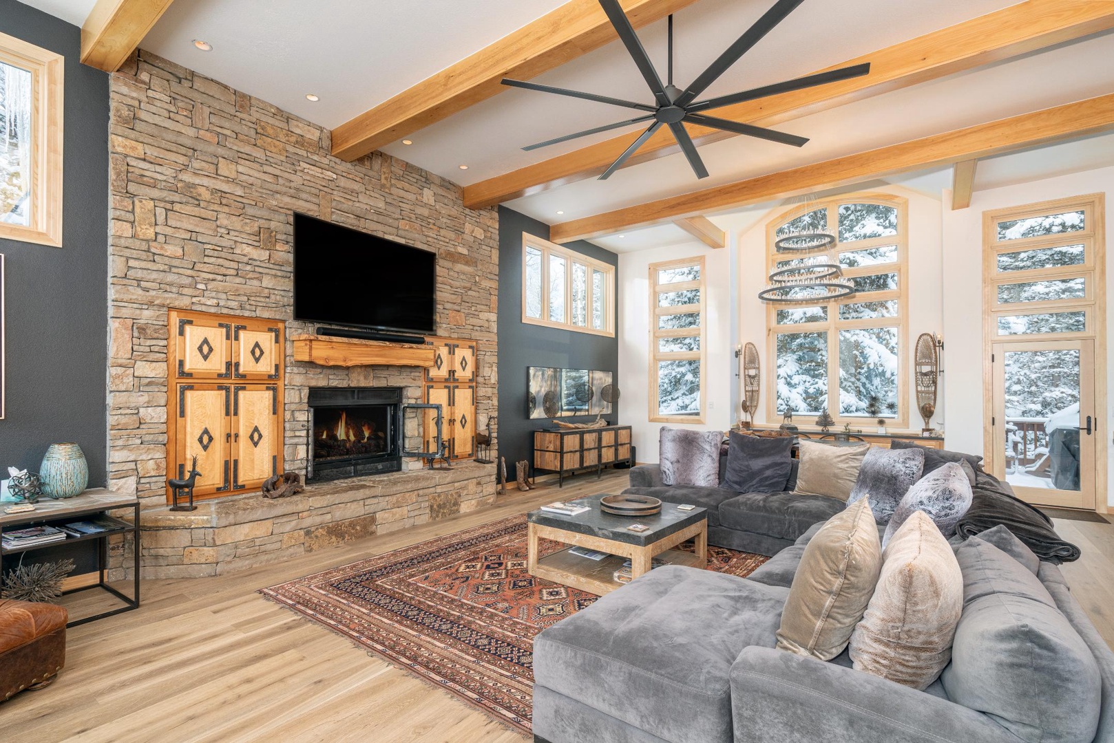Unwind in your spacious living room featuring exposed beams, a cozy stone fireplace, and comfortable seating perfect for relaxing after mountain adventures.