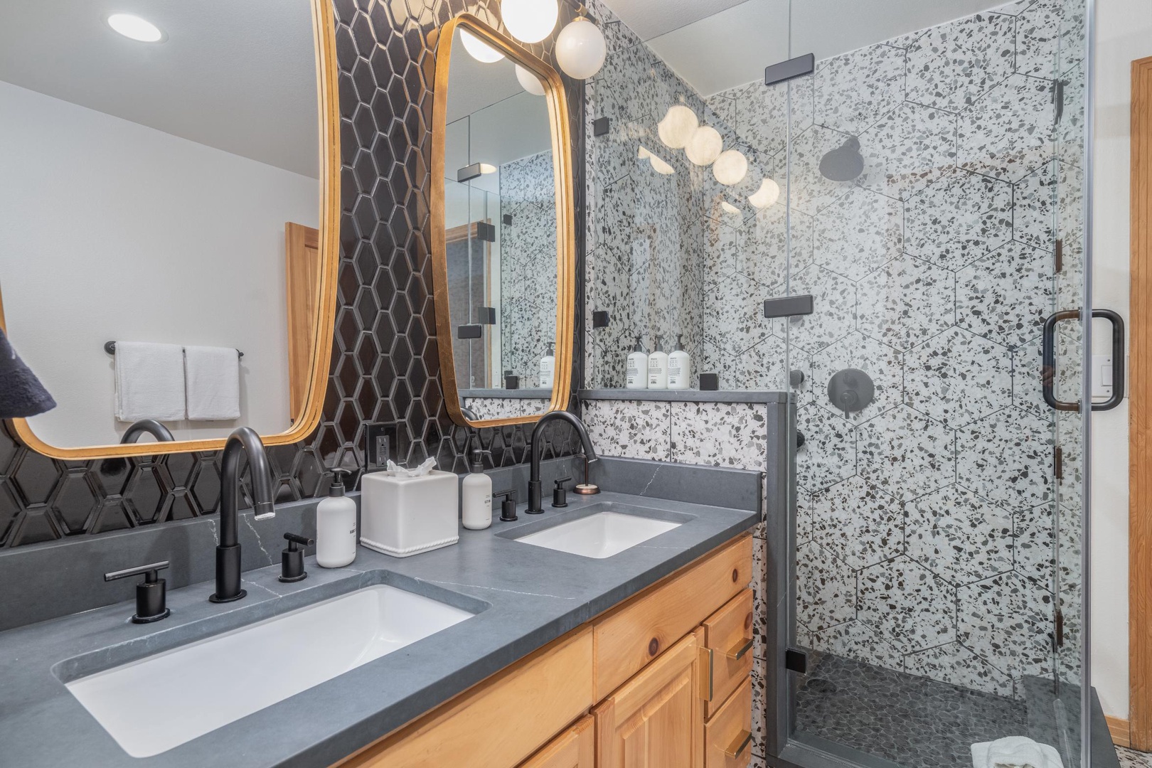 Step into your beautifully appointed bathroom featuring dual vanities, designer tile work, and a spacious glass-enclosed shower with modern fixtures.