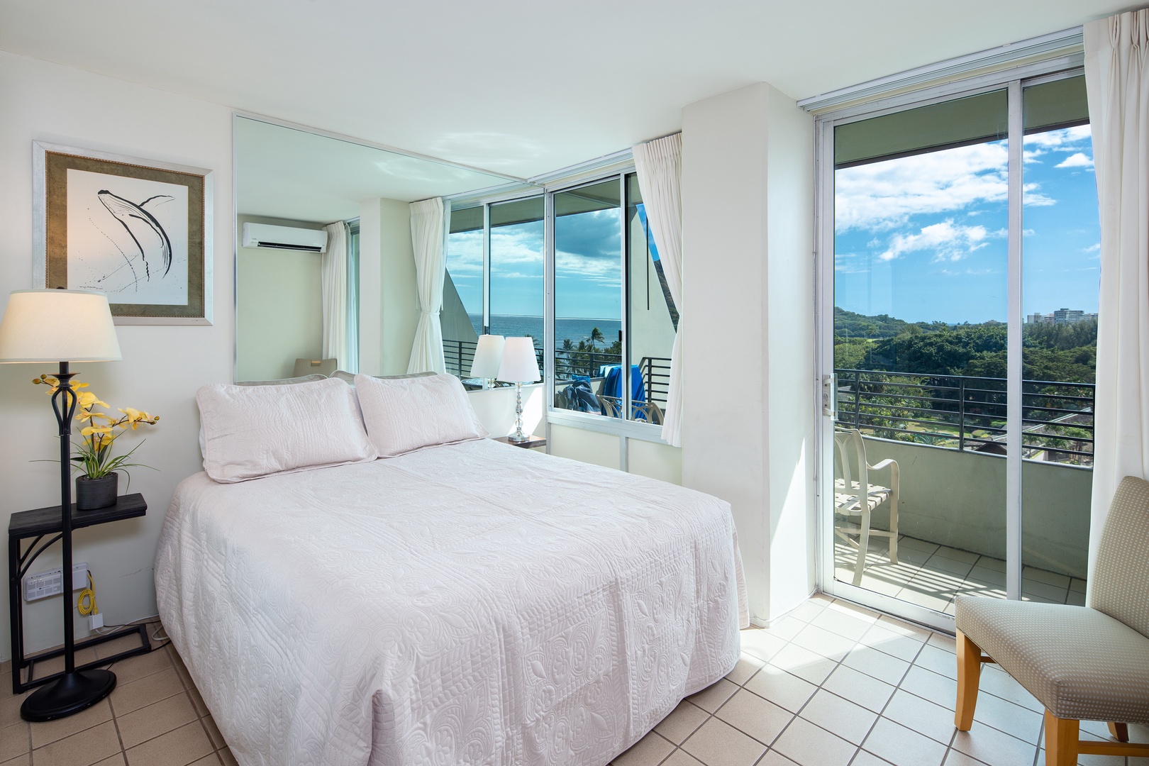 Wake up to ocean breezes and stunning views from your plush bed, framed by floor-to-ceiling windows opening to your private balcony. The crisp linens invite relaxation, while gentle light fills this airy coastal retreat.