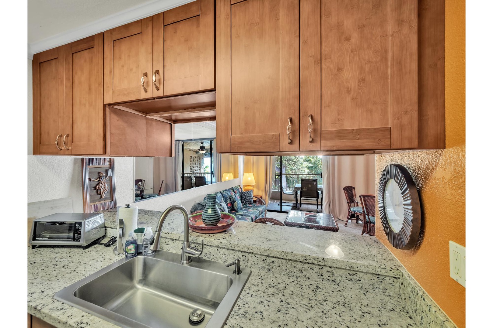 Your modern kitchen features granite countertops, warm wood cabinets, and stainless steel appliances, with an open view to the cozy living area.