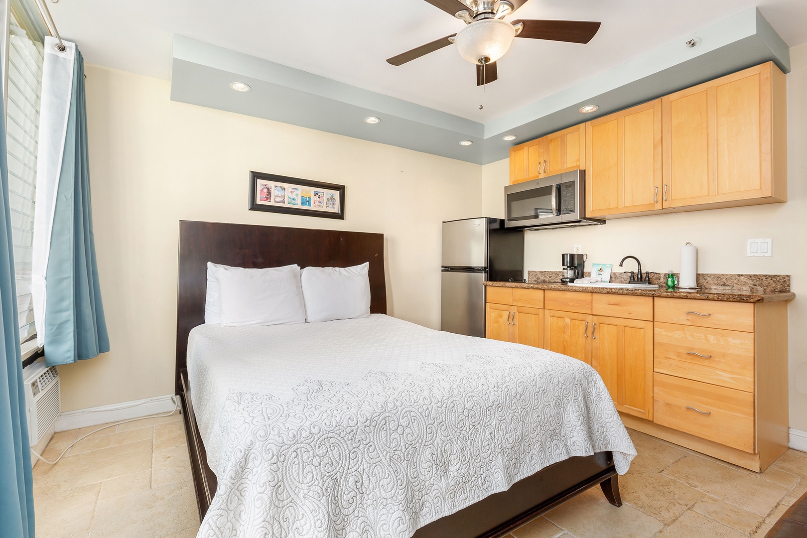 Step into your cozy studio with crisp linens, a full kitchenette, and cool breezes from the ceiling fan—everything you need for a comfortable stay.
