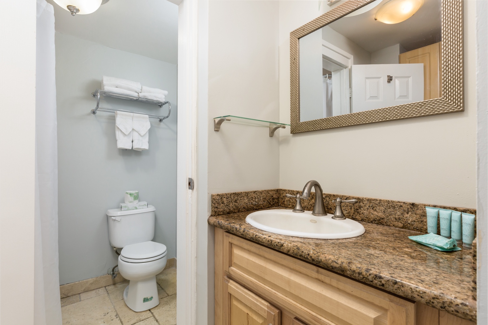 Your bathroom features a granite vanity, fresh linens, and coastal-inspired accents. The soft blue walls and natural wood finishes create a calming retreat after your beach adventures.