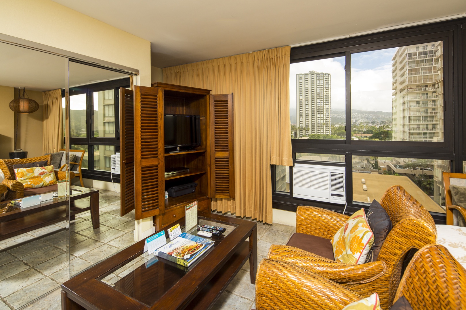Relax in your island-style living space with comfortable woven seating and entertainment center. Panoramic windows frame the city skyline while cool air conditioning keeps you refreshed. Your private urban retreat awaits.