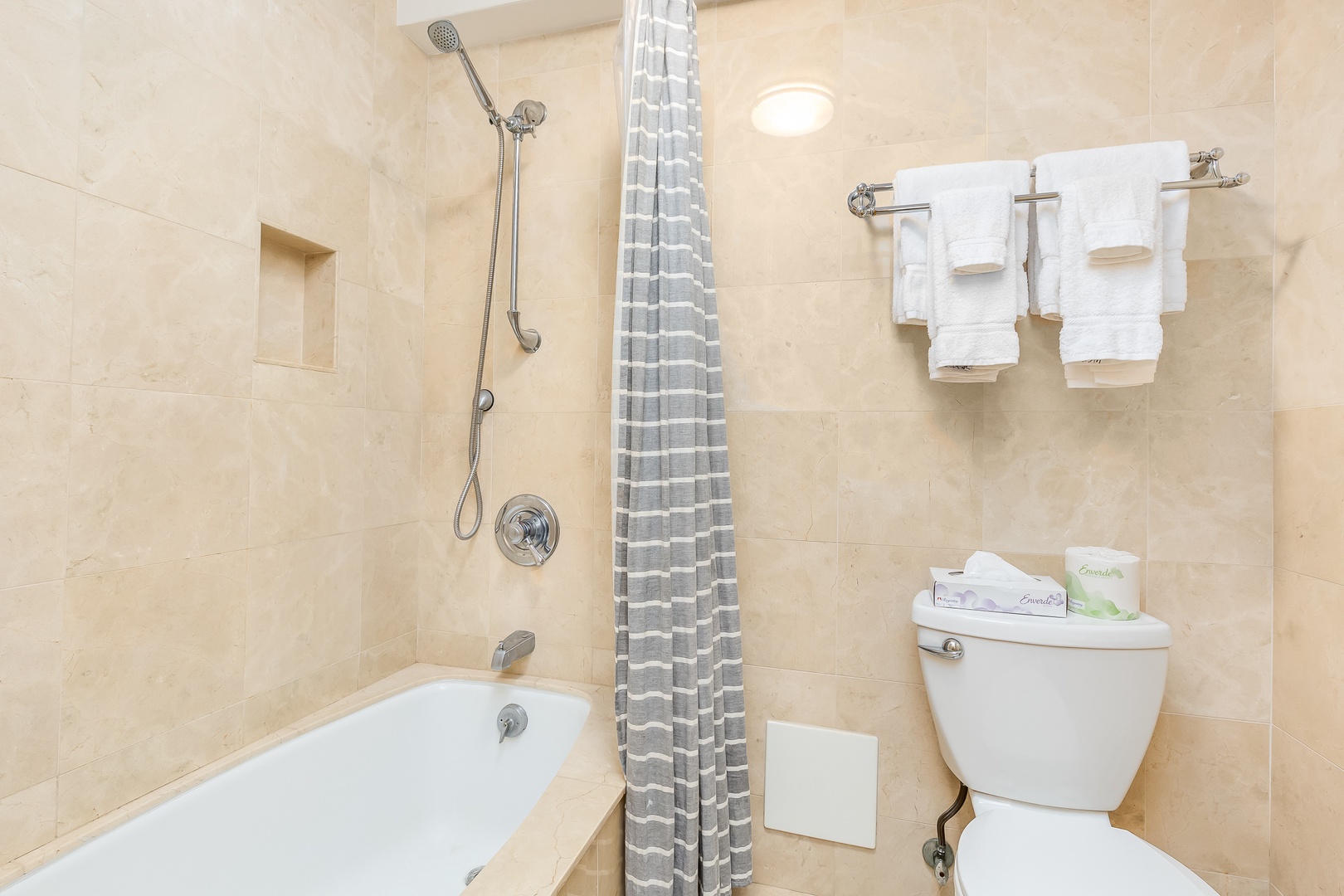Your private bathroom features a sleek tub-shower combo with soft neutral tones, fresh towels, and everything you need for comfort and convenience.