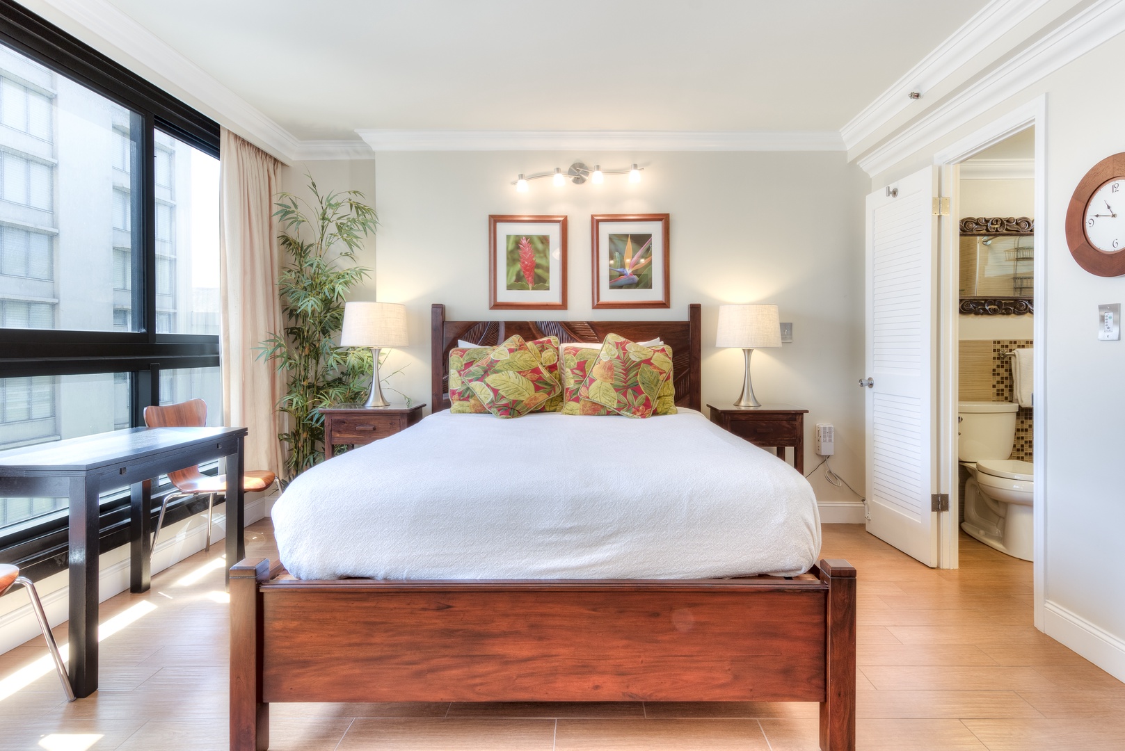 Picture yourself waking up in this tranquil bedroom—soft morning light, a plush bed, and tropical art inviting relaxation. Step onto your private balcony or refresh in the ensuite bathroom.