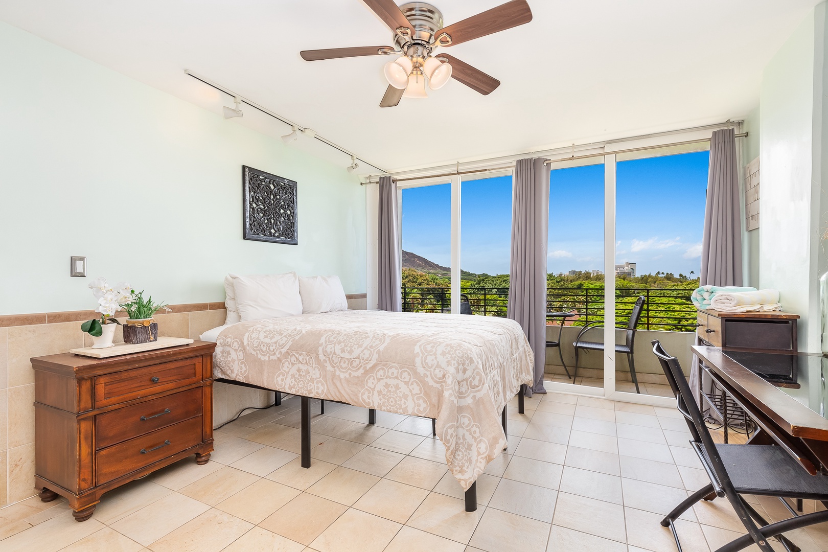 Wake up in your serene bedroom where a ceiling fan keeps you cool and floor-to-ceiling doors open to your private balcony, offering breathtaking mountain and ocean views to start your day.