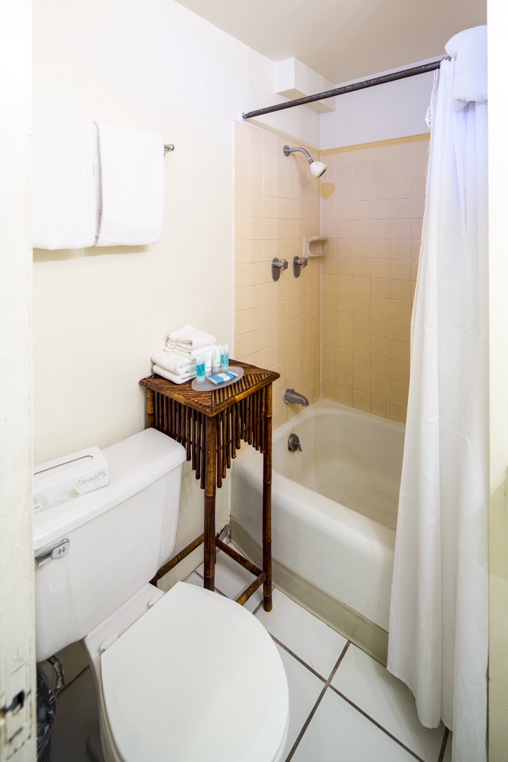 Step into your private bathroom with a cozy tub-shower combo, fresh towels, and essentials neatly arranged for your comfort and convenience.