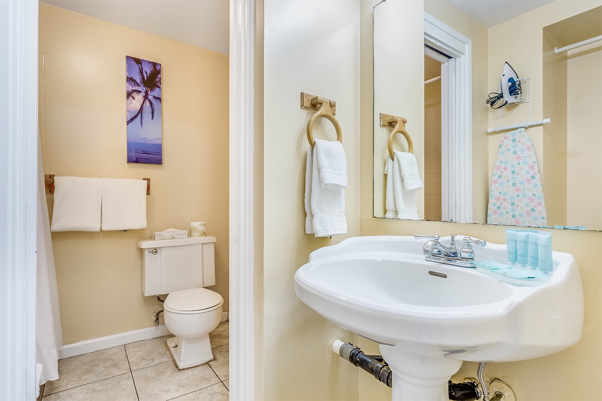 Your private bathroom features a bright sink area and separate toilet room, with fresh towels and coastal art to set a relaxing vacation mood.