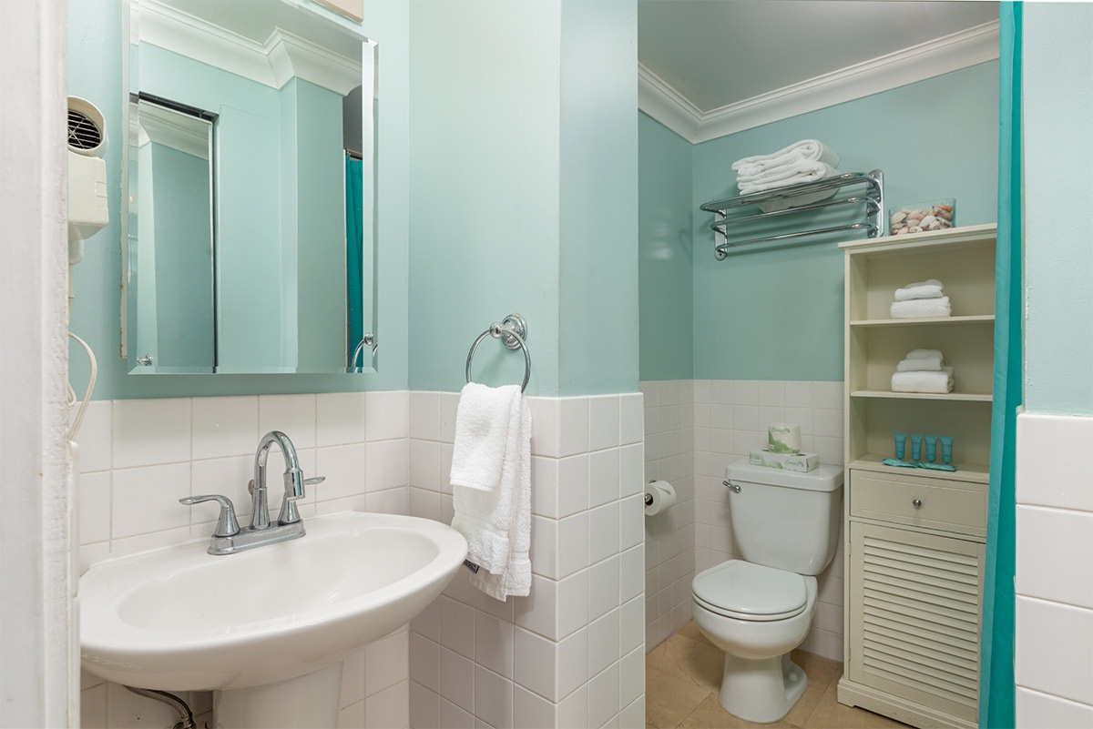 Refresh in your private bathroom with soft aqua walls, crisp white tile, and plush towels ready for you. Everything you need is thoughtfully arranged and waiting.