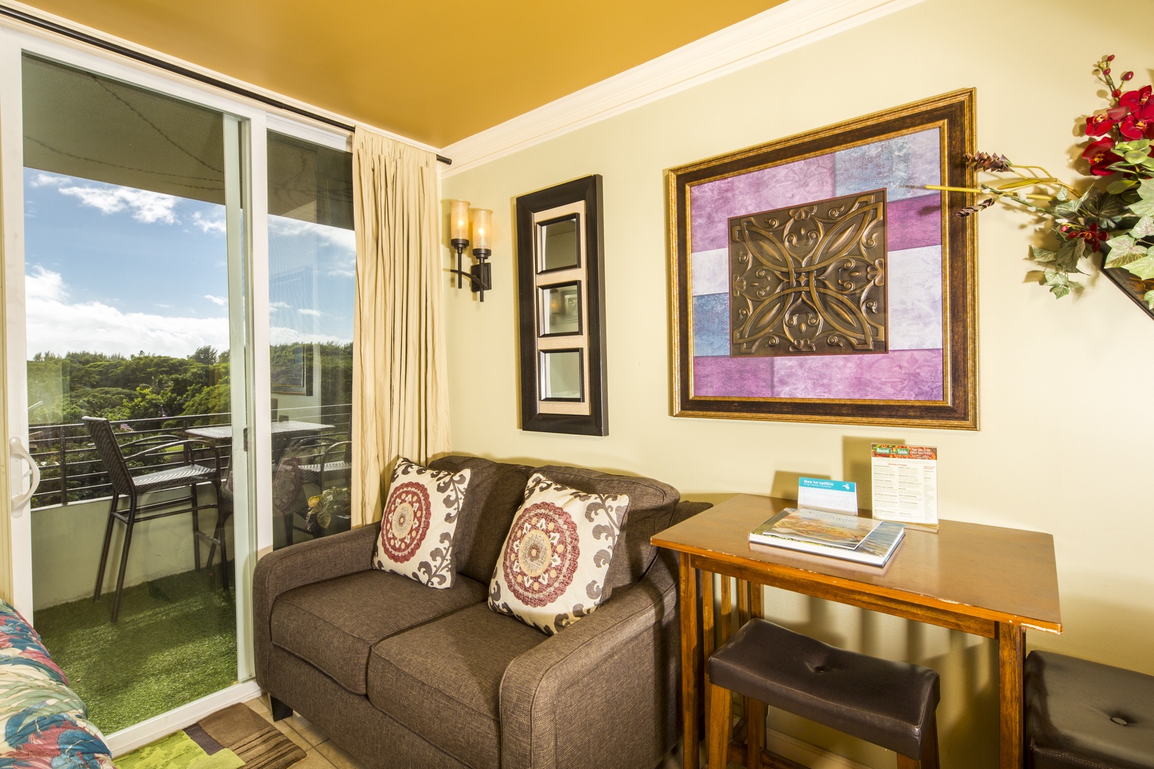 Settle into your cozy living space where sunny skies and lush greenery await just beyond the balcony doors. Plush seating, warm pops of color, and natural light create the perfect spot to unwind.