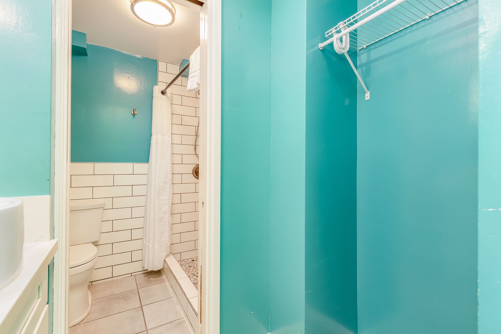 Your private bathroom features bright coastal colors, crisp white subway tile, and a refreshing rain shower. Towels and storage are within easy reach to help you feel right at home.