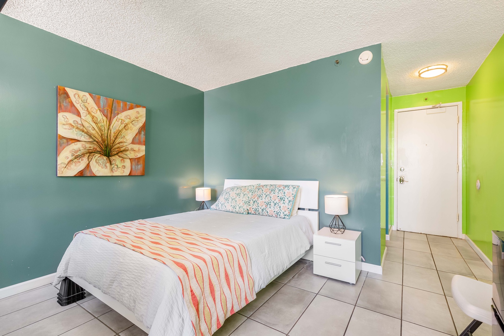Step into your cheerful retreat with vibrant teal walls and crisp white linens that invite restful nights. Modern lamps frame your bed, while colorful artwork adds warmth to your personal escape.