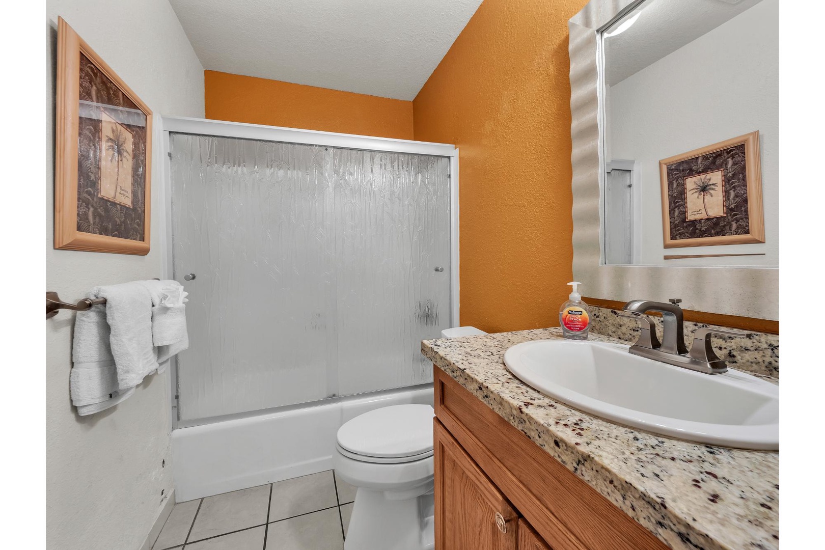 Step into your cheerful private bathroom featuring warm orange accents, granite countertops, and a relaxing tub-shower combo for unwinding after your adventures.