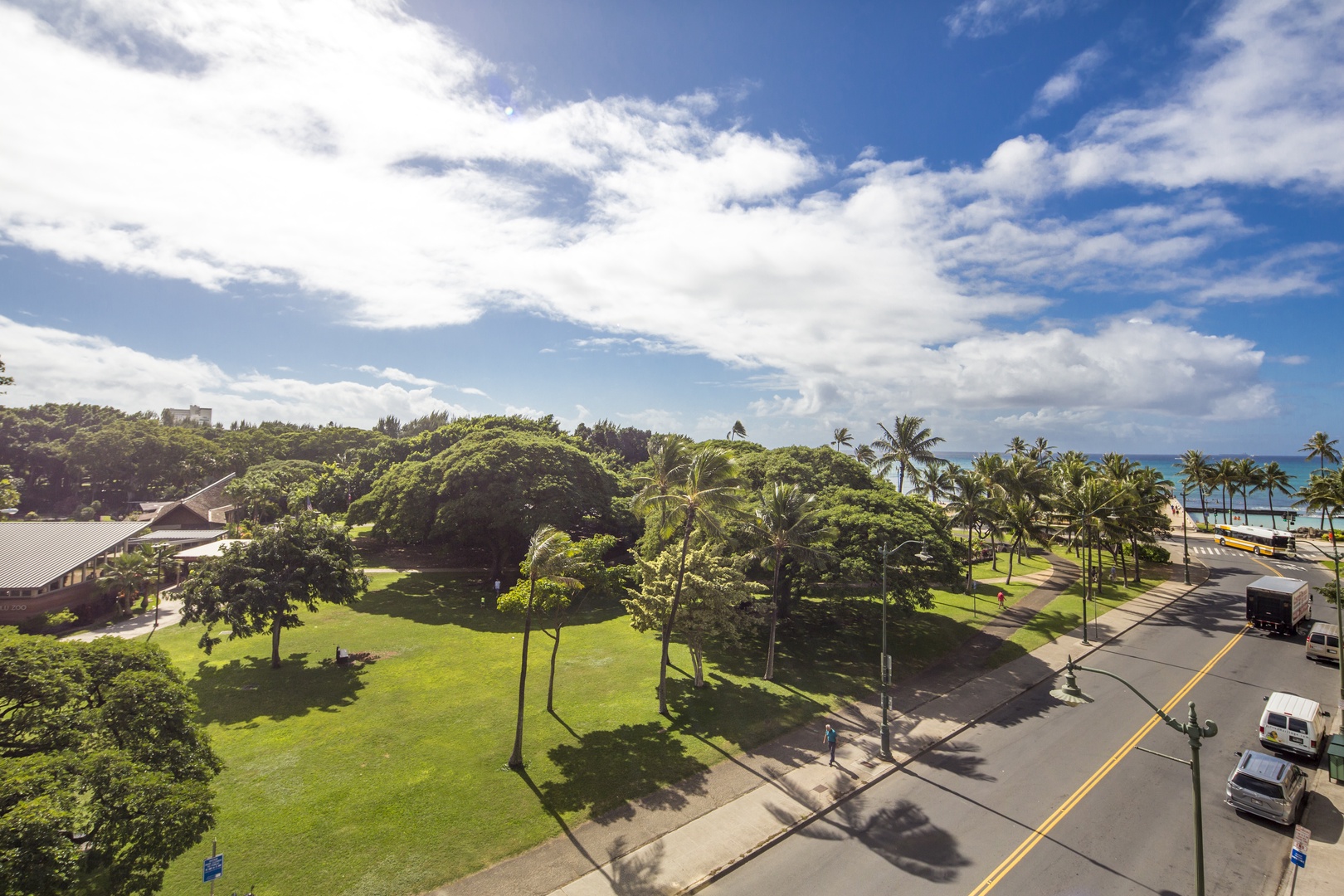 Beachfront property nestled between lush tropical landscaping and pristine ocean views, with palm trees lining the coastal road and expansive green spaces surrounding the main building.