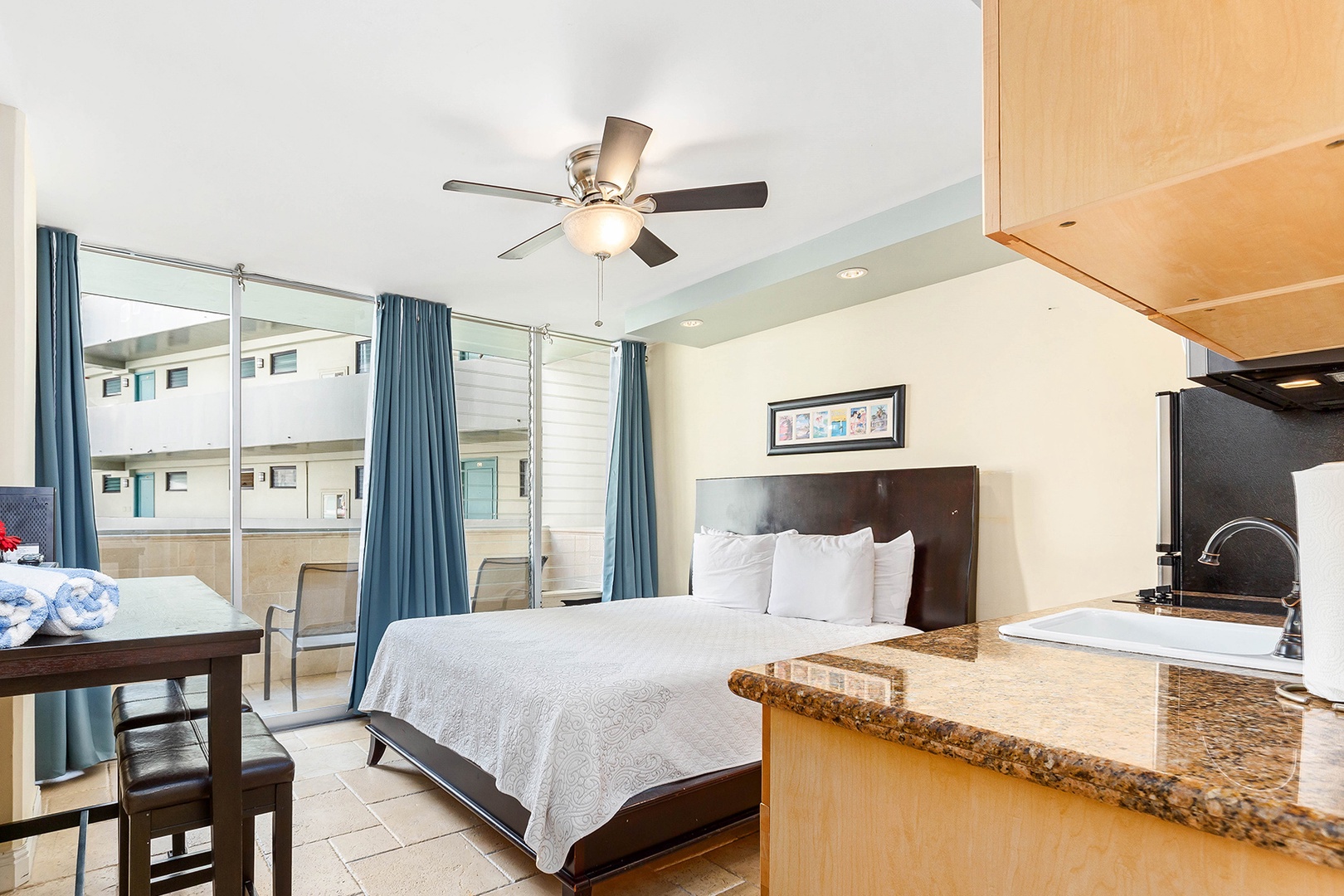 Step into your bright retreat with a plush bed, modern kitchenette, and private balcony. The ceiling fan keeps you comfortable as you unwind in style.