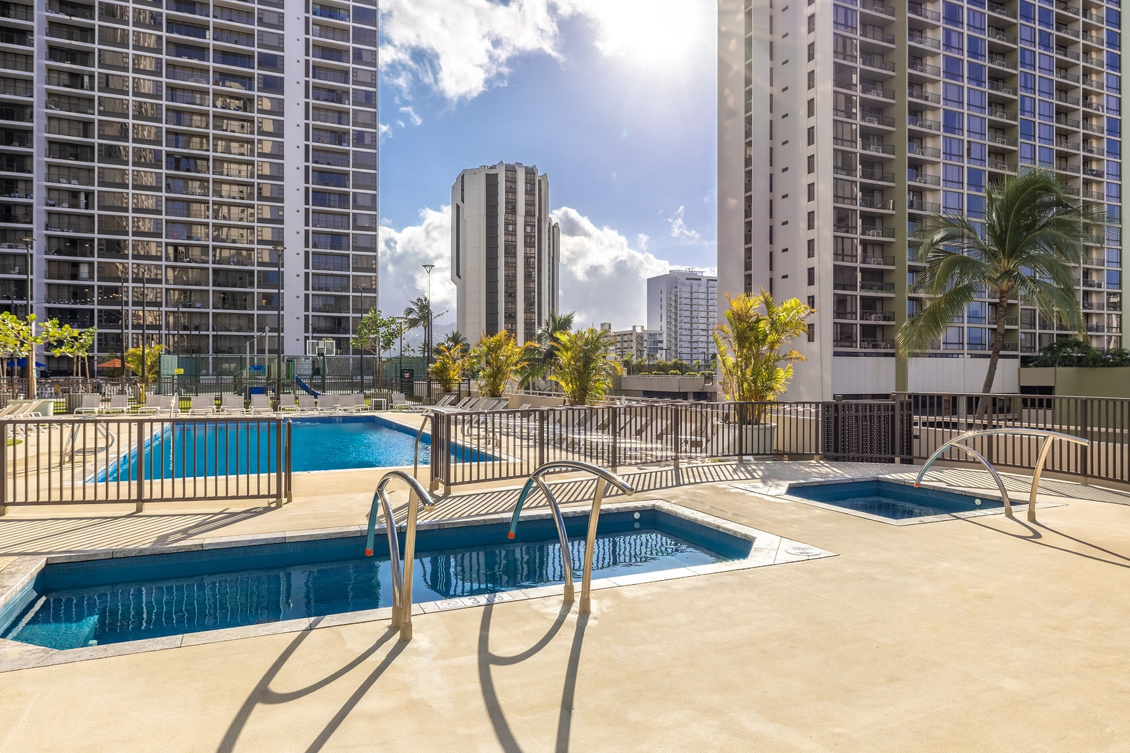 Multiple pool areas await, framed by tropical palms and surrounded by the vibrant cityscape—perfect for sunny days in paradise.