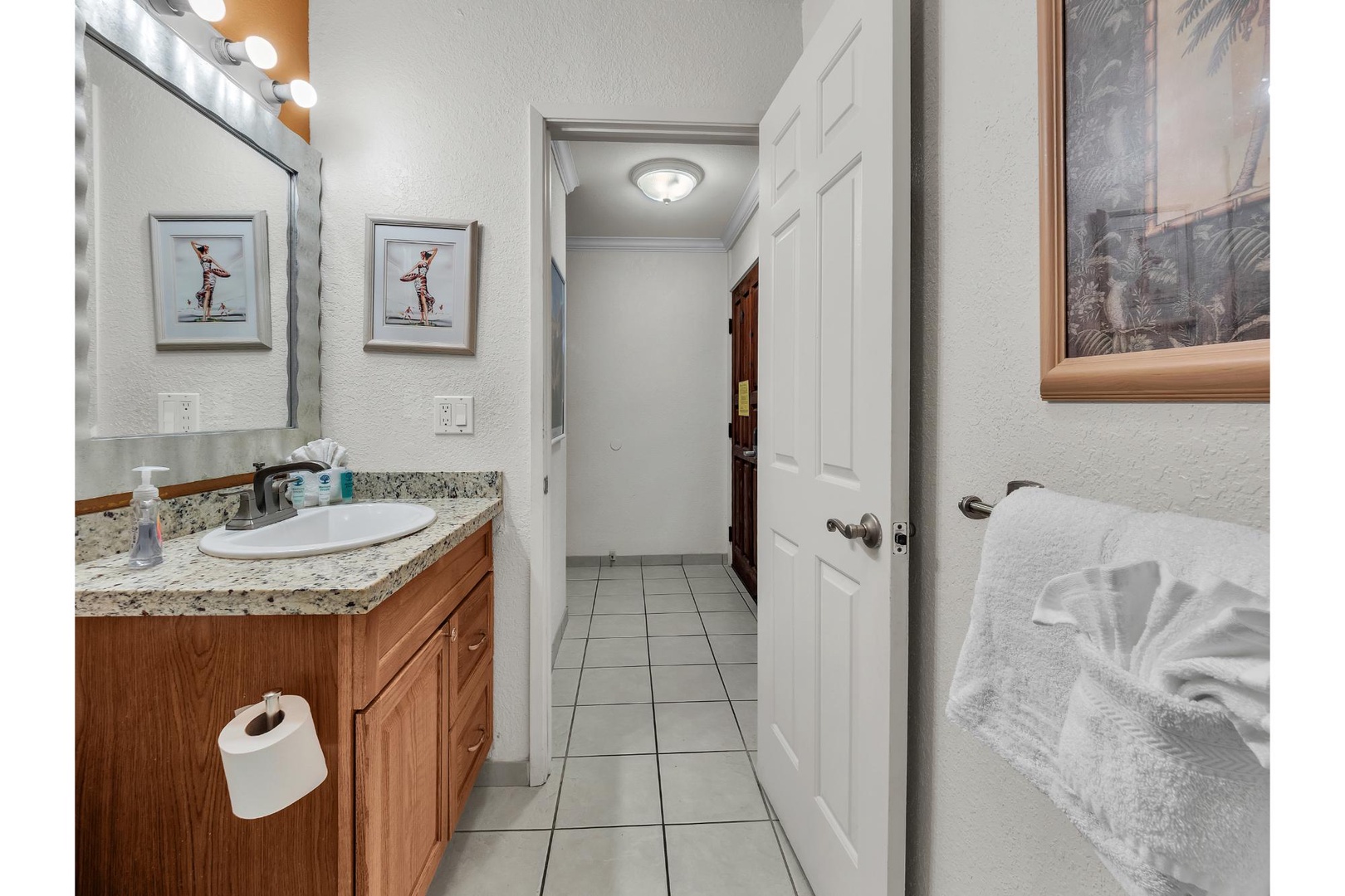 Step into your pristine bathroom with granite countertops, warm wood vanity, and plush towels ready for your relaxing soak.