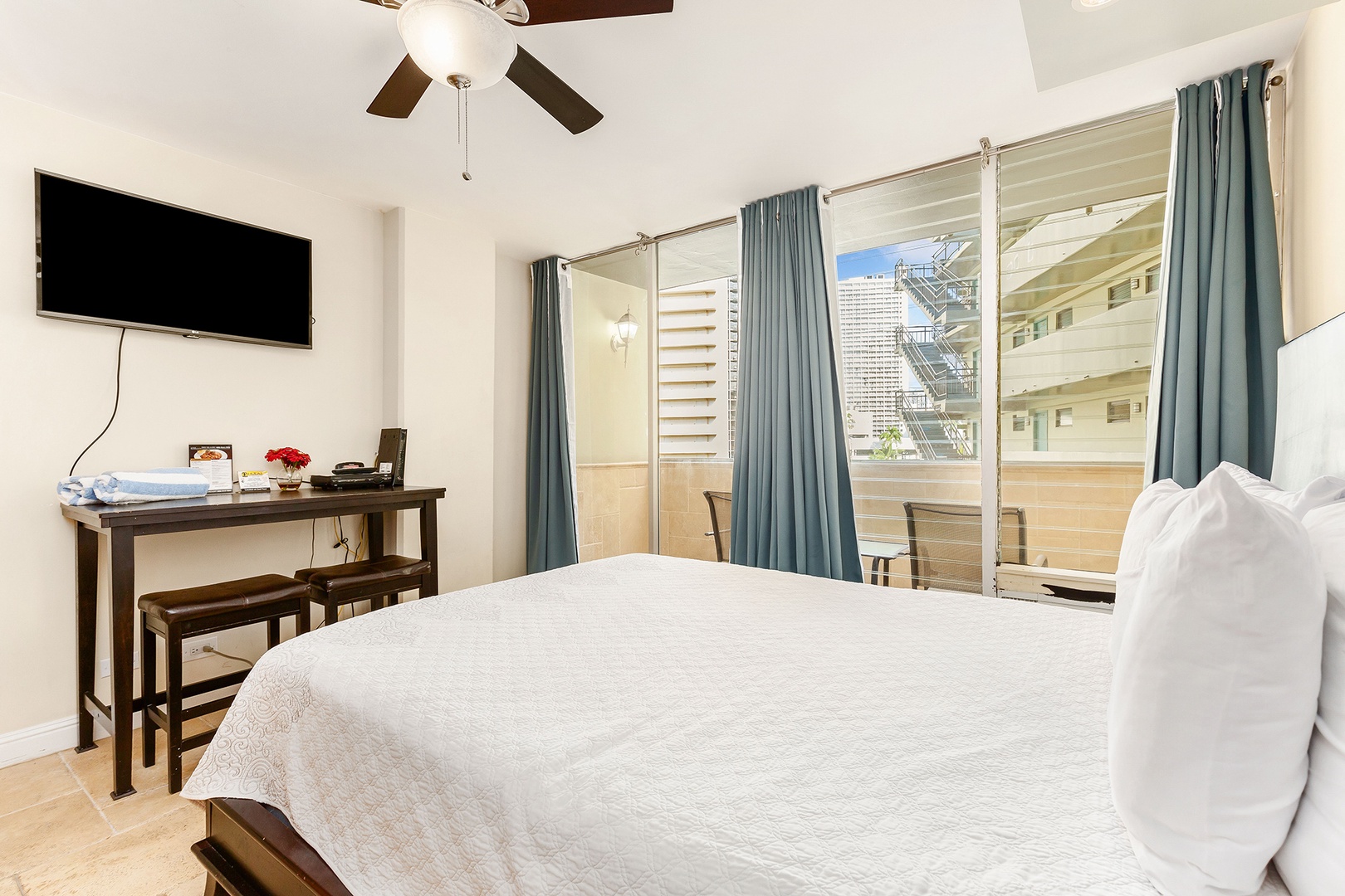 Your bright, comfortable bedroom offers a ceiling fan, flat-screen TV, and private balcony access with sliding doors—perfect for relaxing after a day of exploring.