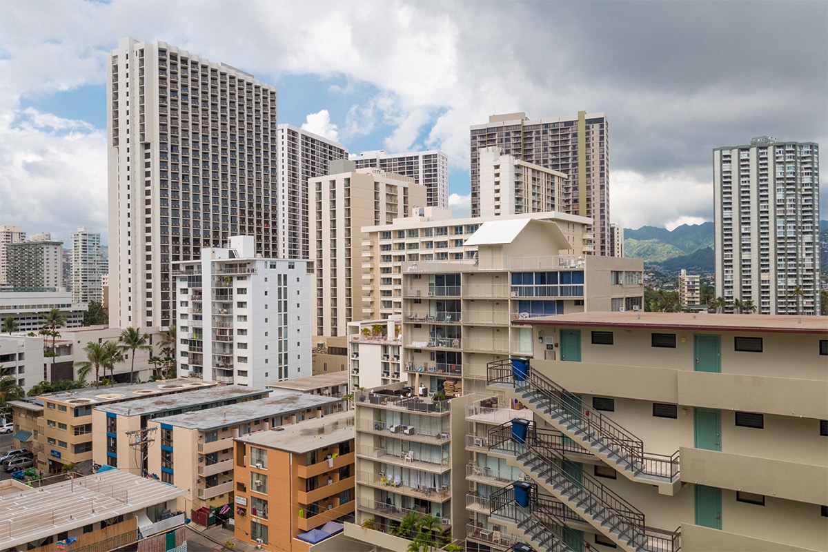 The property is located in a vibrant urban neighborhood with high-rise buildings and mountain views visible in the surrounding area.