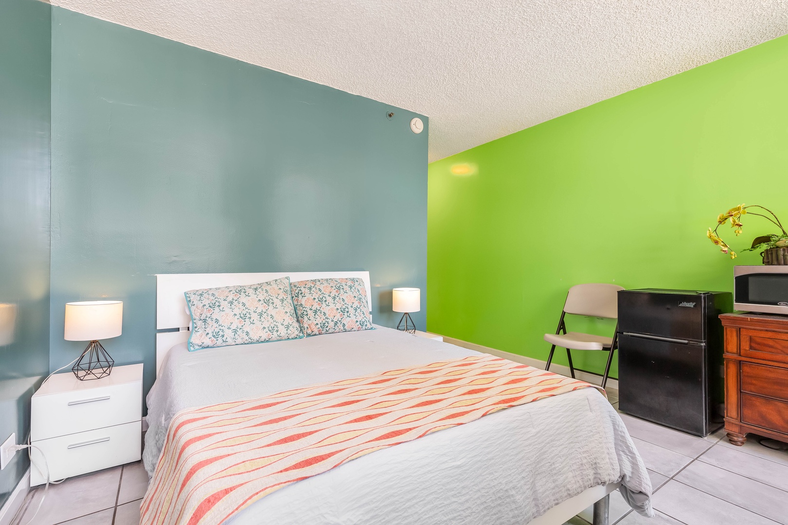 Unwind in this bright, cheerful bedroom with a comfy bed framed by calming blue and energizing green walls, plus modern conveniences at your fingertips.