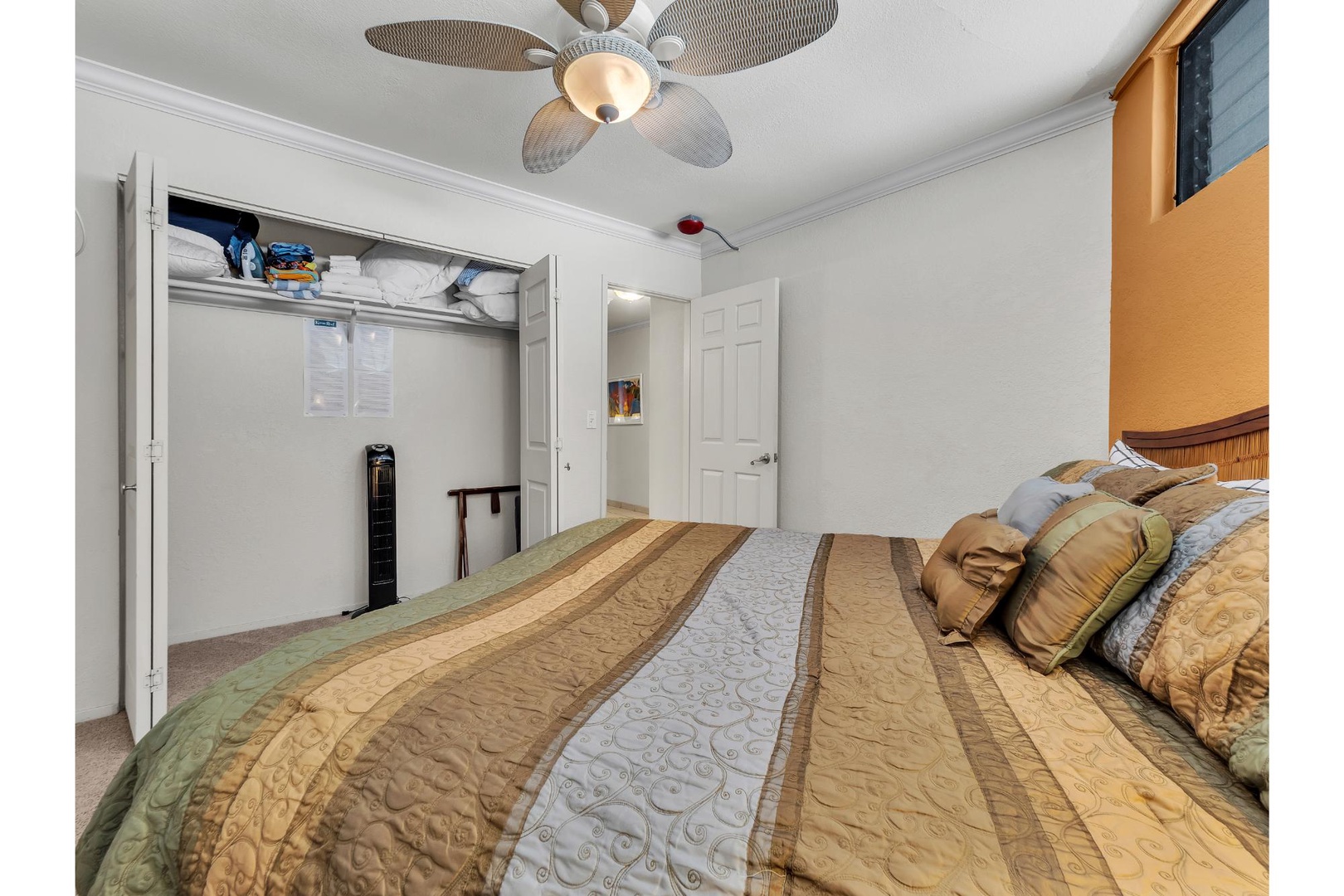 Relax in your comfortable bedroom featuring rich earth-tone bedding and thoughtful touches like a ceiling fan for perfect temperature control.