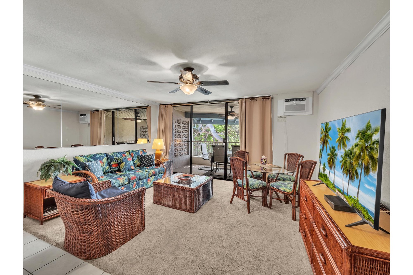 Relax in your tropical-themed living space with wicker furniture, ceiling fans, and a large TV perfect for unwinding after beach days.