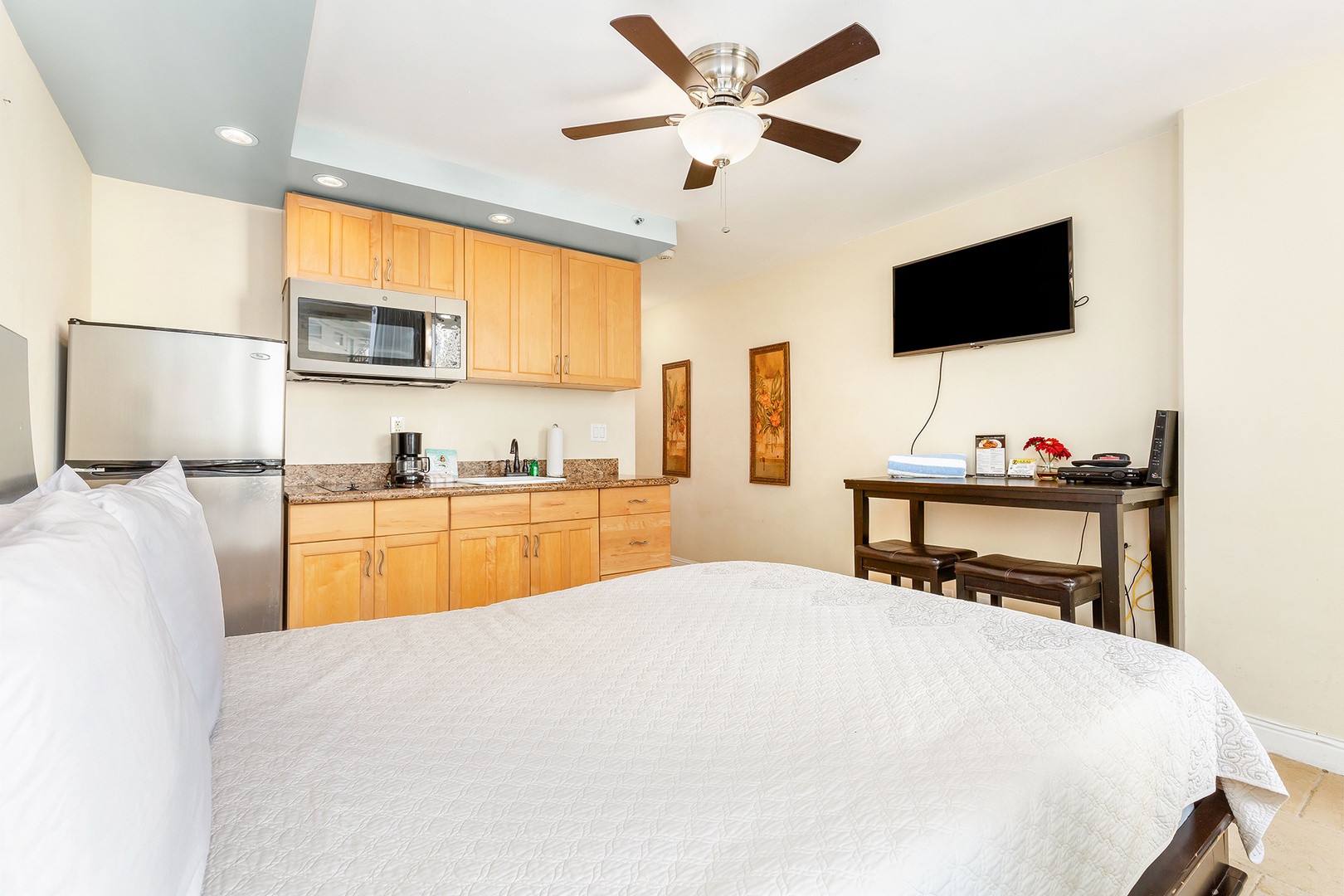 Unwind in your cozy retreat featuring a plush bed, full kitchenette, flat-screen TV, and ceiling fan—everything you need for a comfortable, convenient stay.
