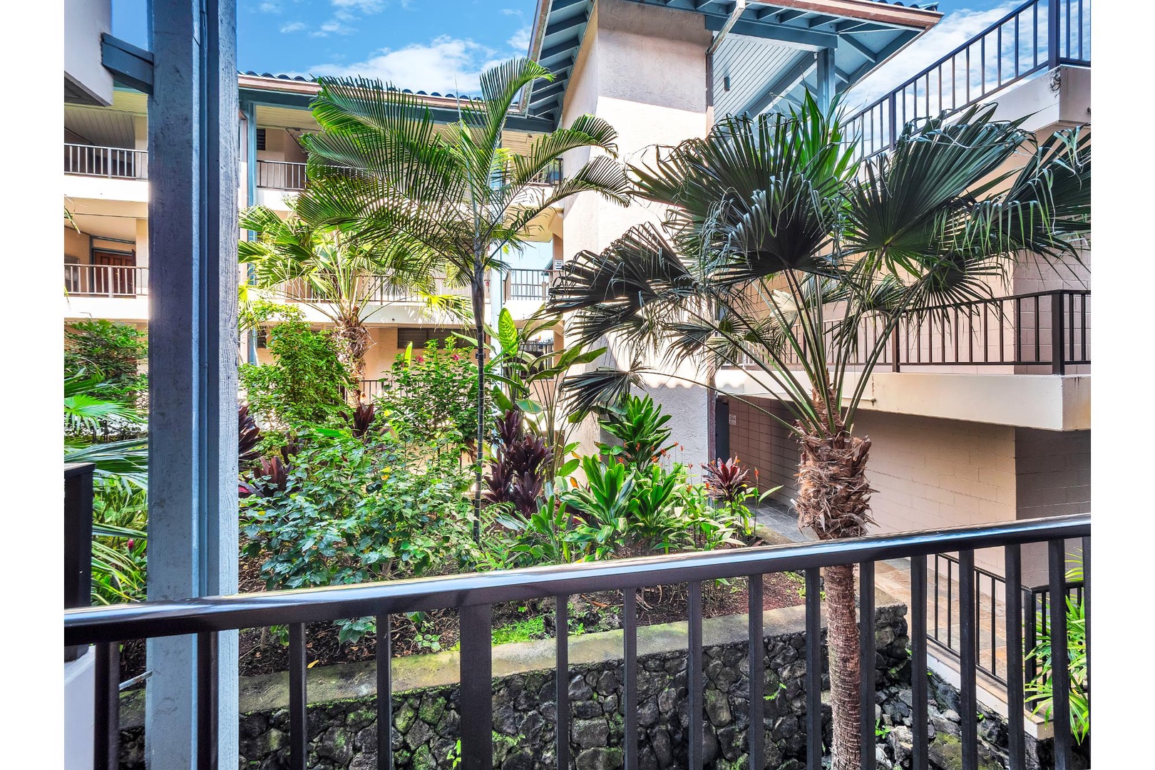 Multi-story vacation rental complex with tropical landscaping and balconies, featuring lush palm trees and well-maintained gardens throughout the property grounds.