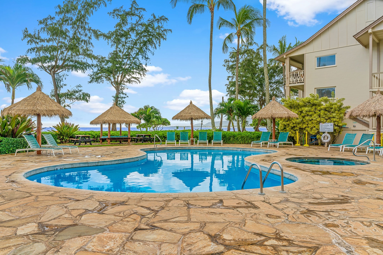 Tropical pool paradise with thatched umbrellas and ocean views creates the perfect backdrop for your island getaway relaxation.