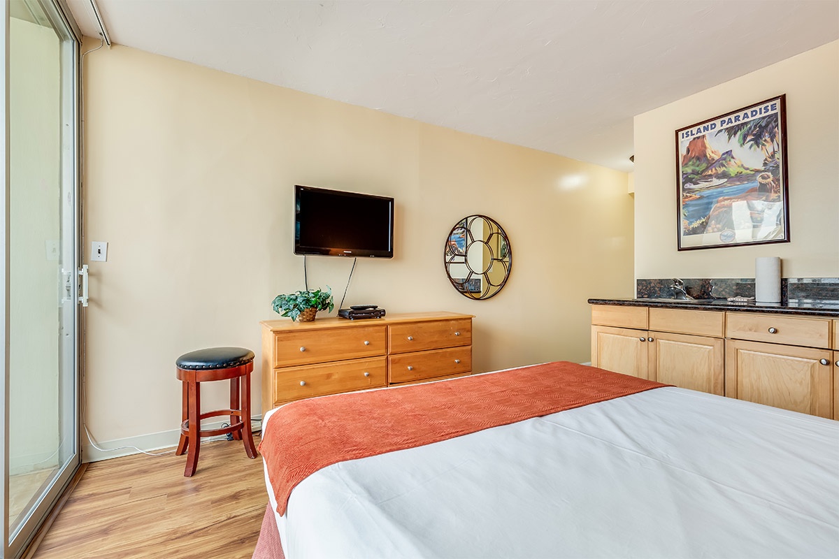 Your cozy bedroom features a comfortable bed, flat-screen TV, and tropical artwork that sets a relaxing island vibe for your getaway.