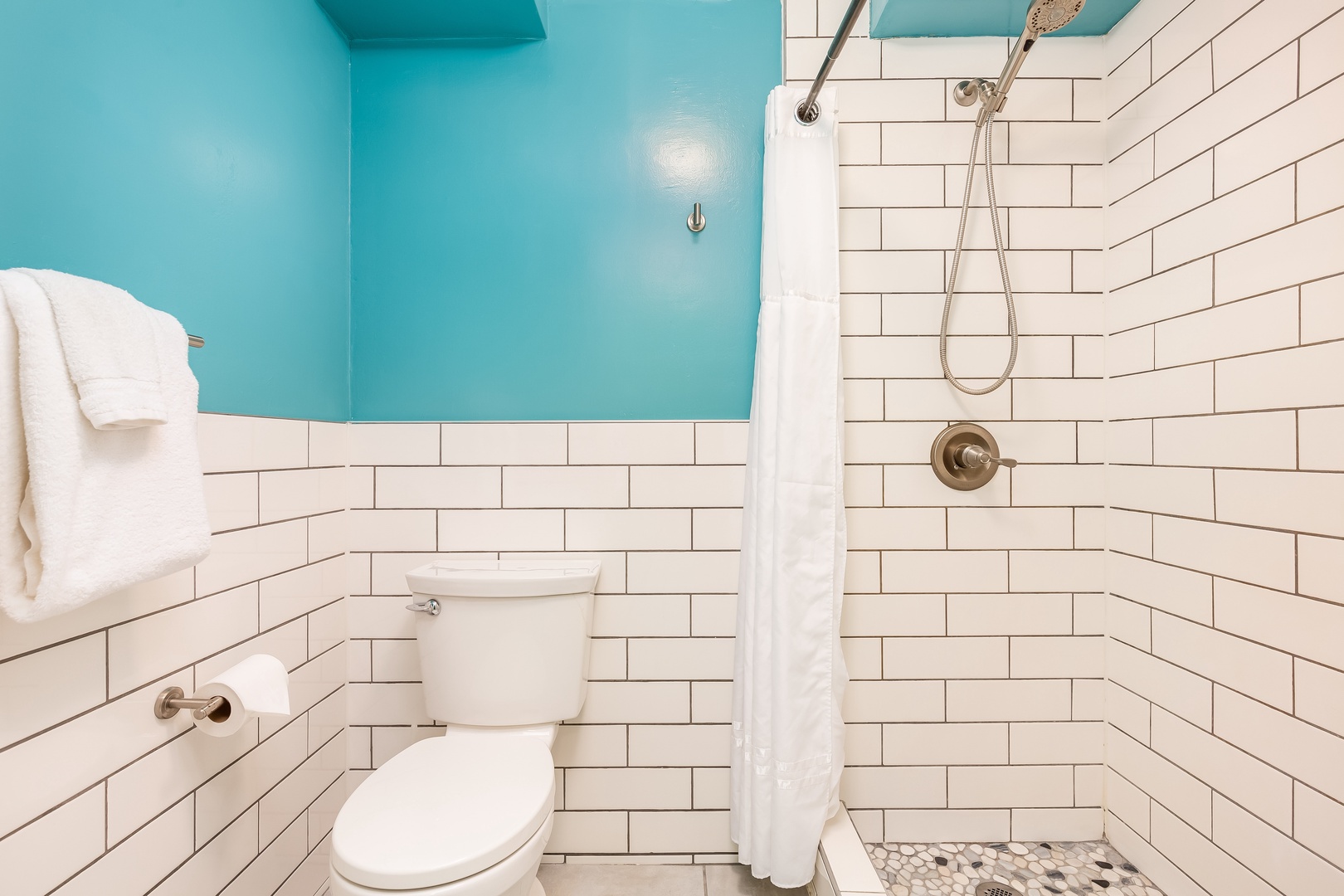 Refresh in a crisp, clean bathroom where white subway tile and cheerful turquoise walls create a bright, welcoming vibe. Fresh towels and a spacious walk-in shower await your arrival.