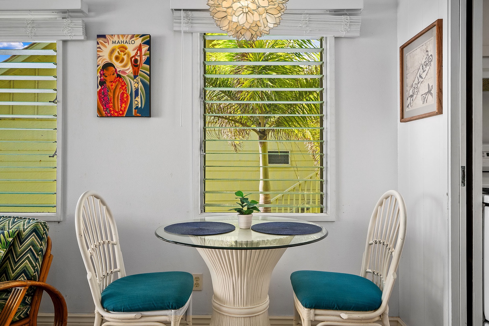 Your intimate dining nook features tropical artwork and garden views through louvered windows, perfect for morning coffee together.