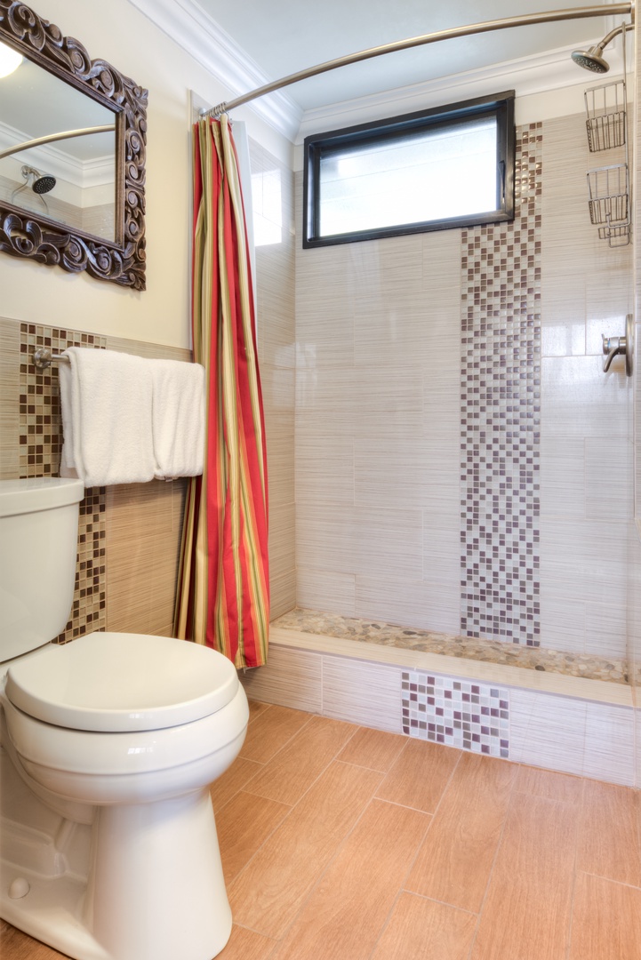 Step into your private bathroom featuring elegant mosaic tile accents, a spacious walk-in shower with rainfall showerhead, and warm wood-look flooring that creates a spa-like retreat.
