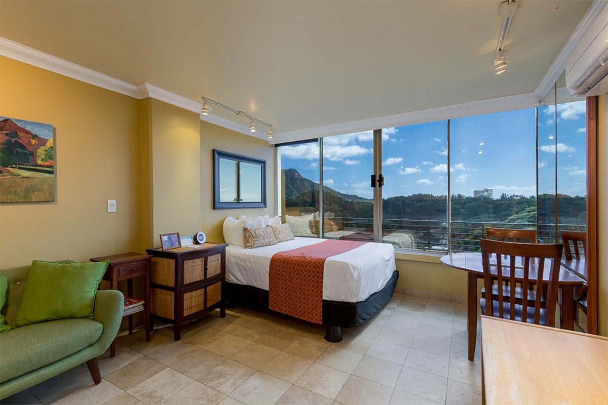 Imagine waking up to this breathtaking mountain view framed by floor-to-ceiling windows, where your private balcony invites morning coffee and peaceful moments. Warm tones and comfortable furnishings make your retreat feel like home.