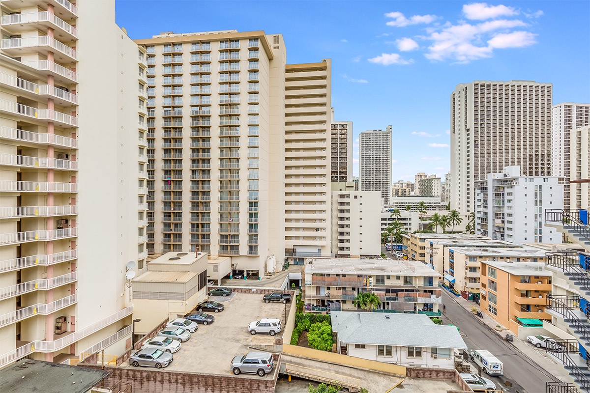 Urban vacation rental set in a vibrant high-rise district with convenient parking lot nearby and surrounding cityscape views featuring modern architecture and sunny skies.