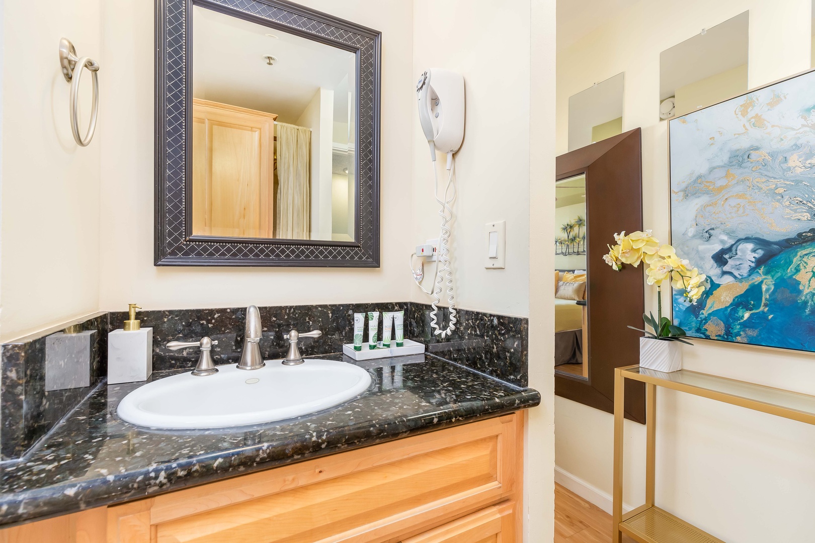 Step into your elegantly appointed bathroom, featuring a sleek black granite vanity, decorative framed mirror, and convenient hair dryer—thoughtful touches that elevate your comfort.