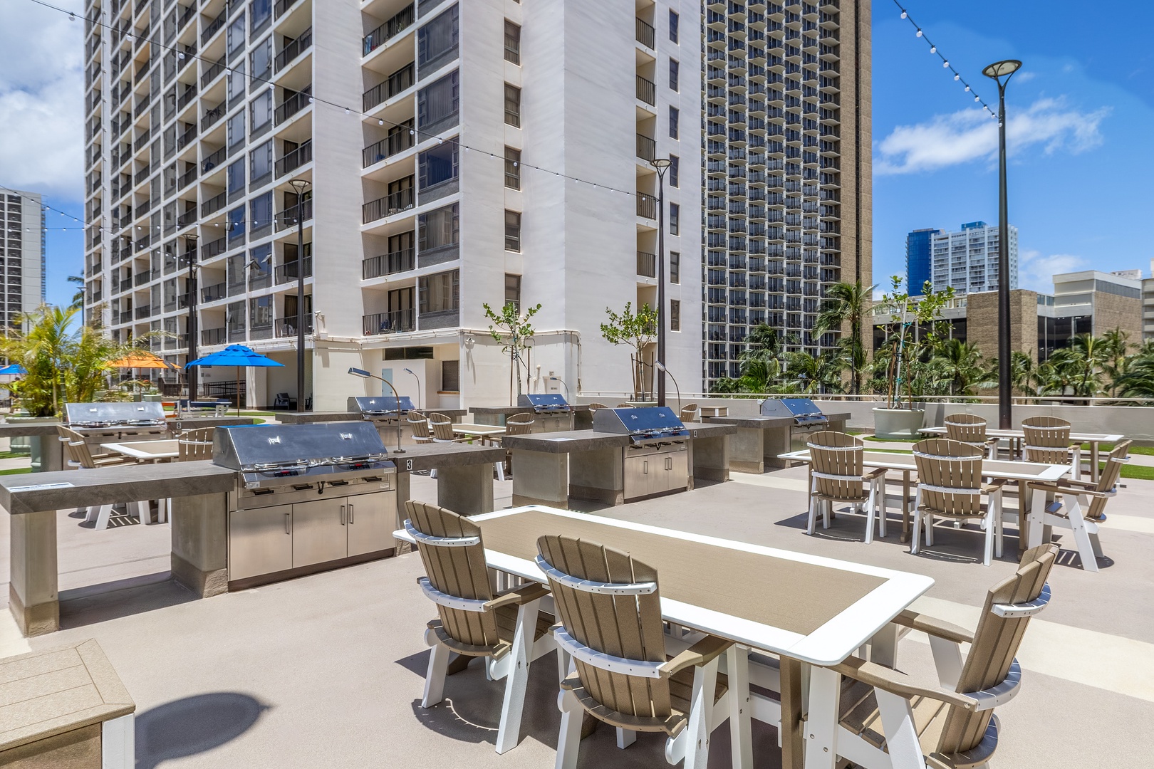 An urban oasis awaits: stainless steel grills, spacious dining tables, and Adirondack-style seating create the perfect outdoor setting for your gatherings under sunny skies surrounded by city energy.