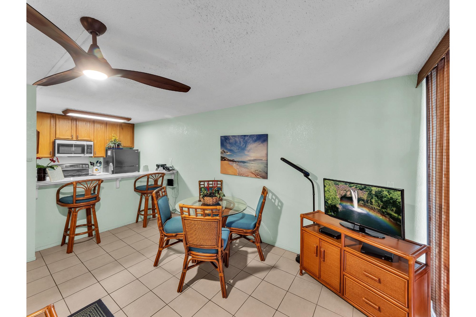 Relax in your tropical-inspired living space with warm wood furnishings, ceiling fan, and entertainment center for cozy evenings.