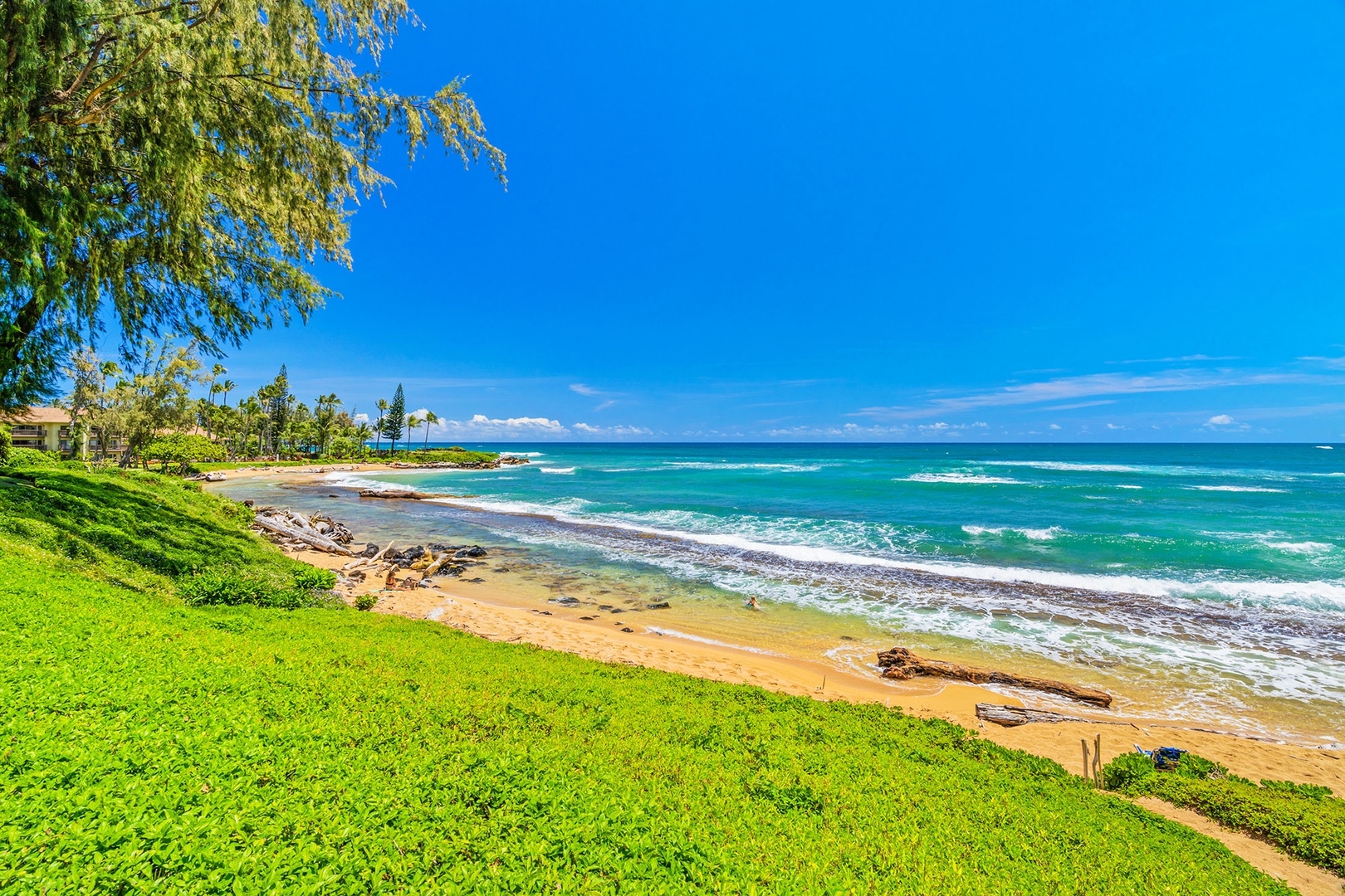 Stunning oceanfront location with pristine sandy beach, turquoise waters, and lush tropical landscaping under brilliant blue skies.