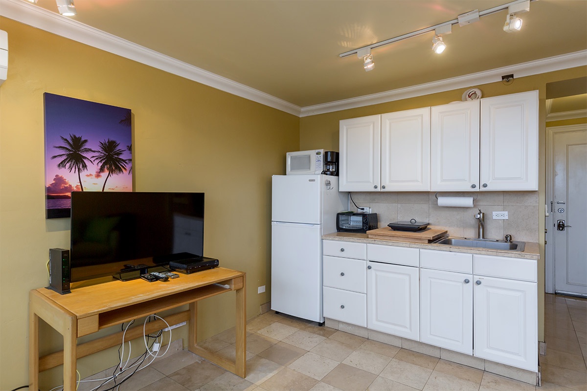 Your fully-equipped kitchenette features crisp white cabinetry, essential appliances, and warm tile floors—perfect for preparing meals during your stay.