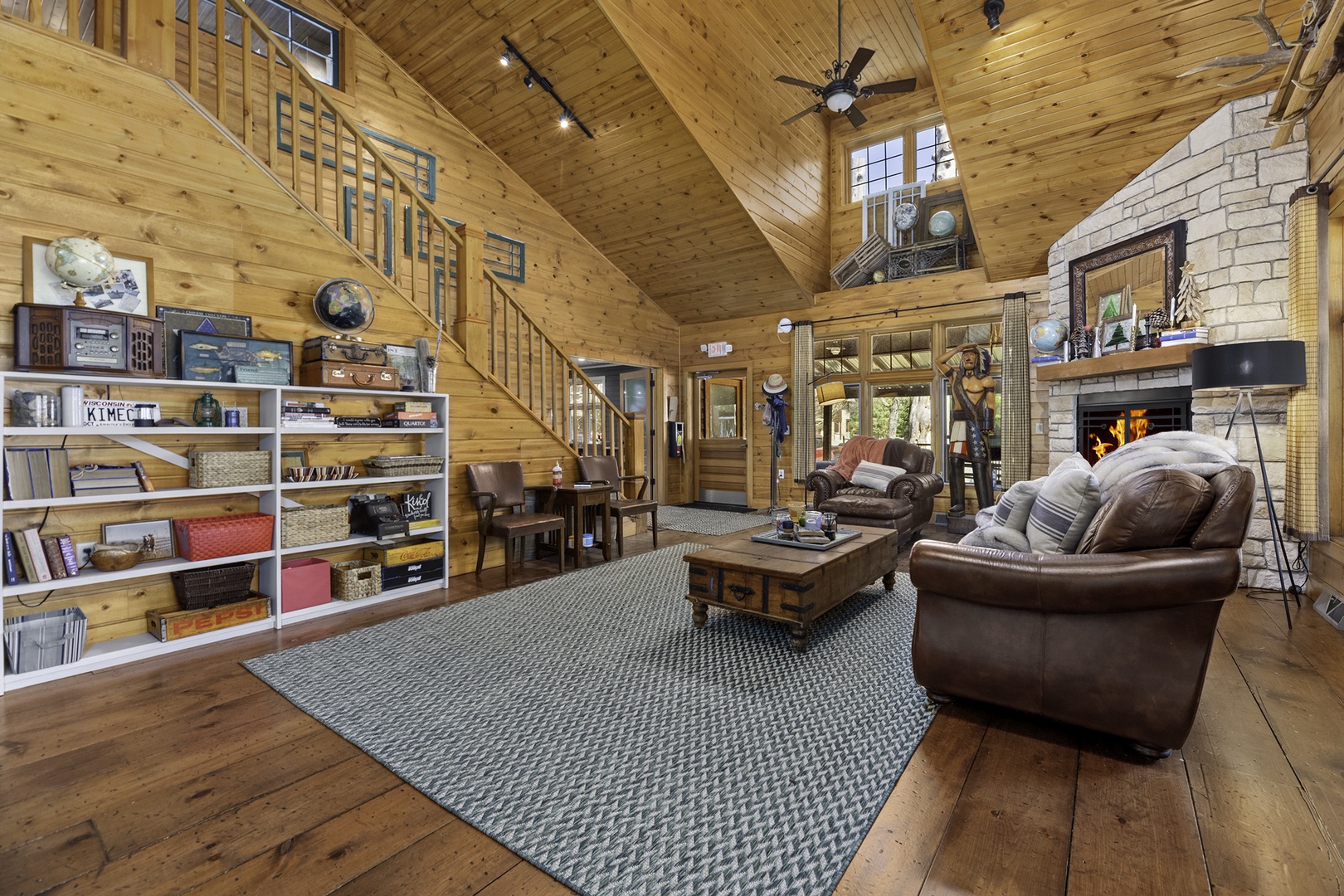 Gather around the crackling fireplace in this inviting living room, where vaulted wood ceilings, cozy leather sofas, and rustic charm create your perfect retreat.