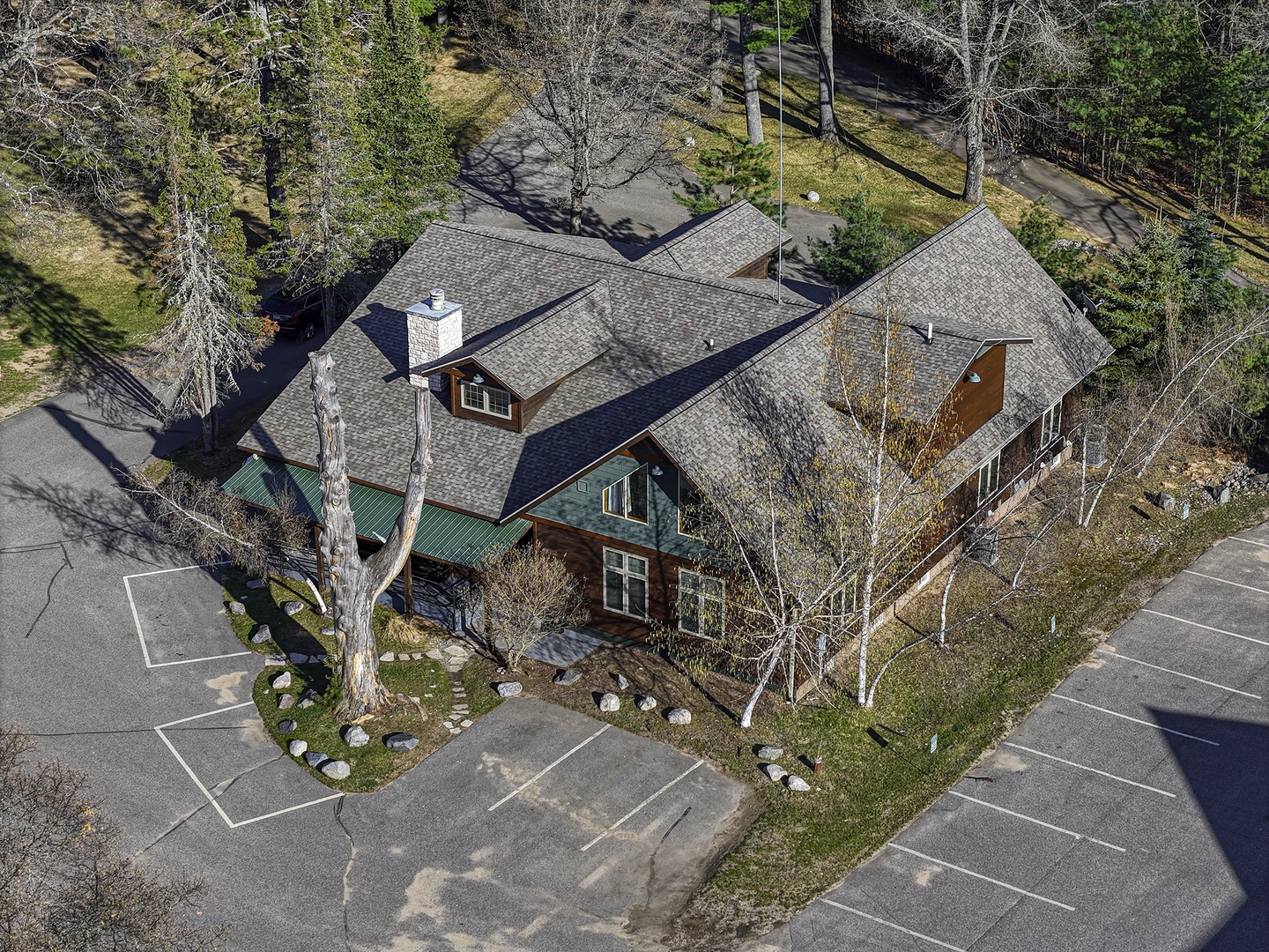 Aerial view of a charming  retreat nestled among tall pines and aspens, with ample parking and a peaceful natural setting in the surrounding area.