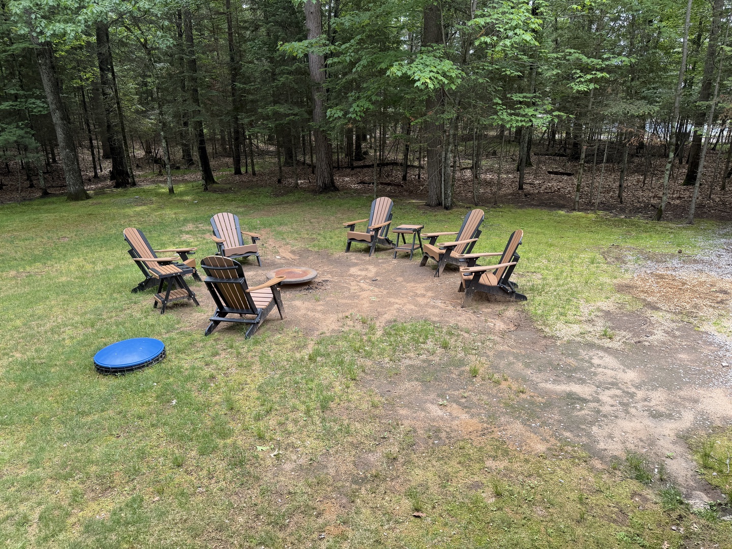 Gather around the fire pit with loved ones, surrounded by peaceful woods. Six Adirondack chairs invite you to unwind, share stories, and make memories under the trees.