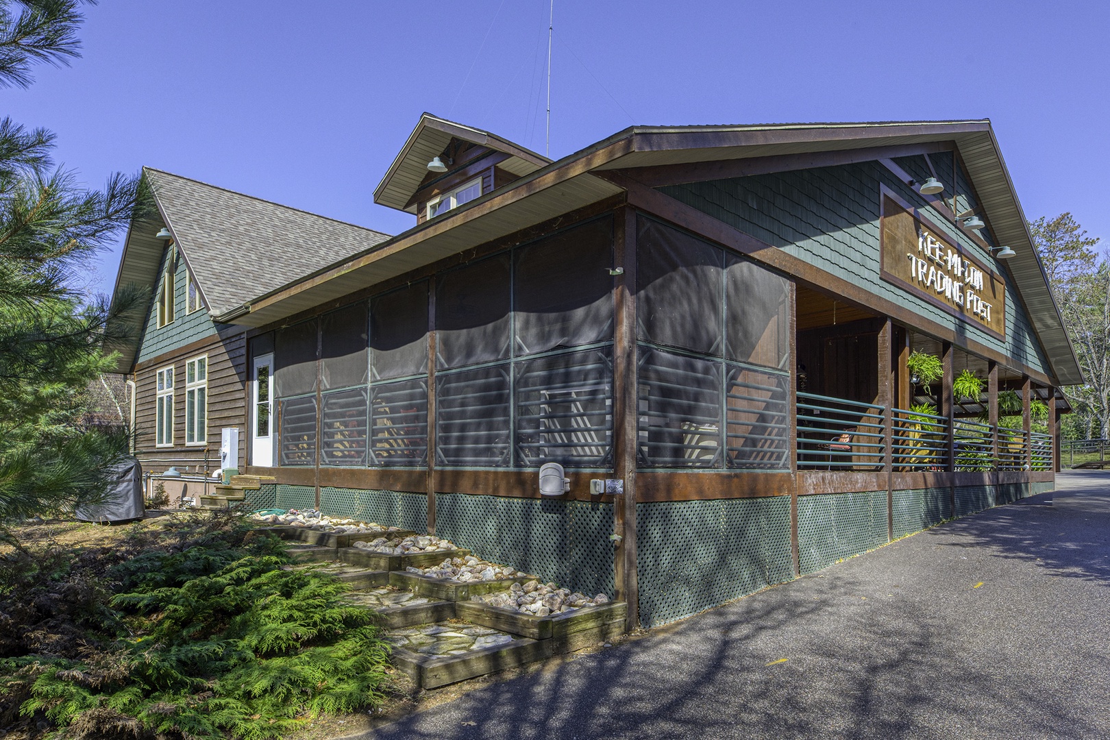Quaint  lodge with screened wraparound porch nestled in a peaceful  setting, offering guests a serene retreat surrounded by nature.
