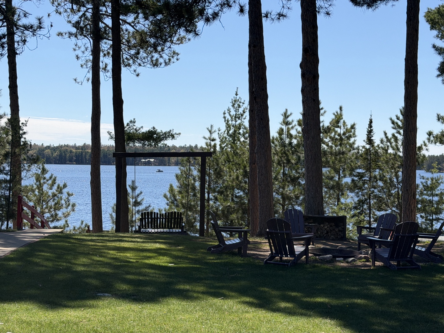 A peaceful lakefront property surrounded by tall pines, featuring a private fire pit area and tranquil water views—ideal for quiet mornings and evening gatherings.