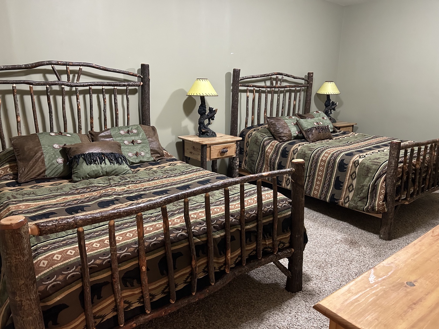 Rest easy in your rustic twin bedroom featuring charming log-style beds with cozy wilderness-themed linens and warm bedside lighting.