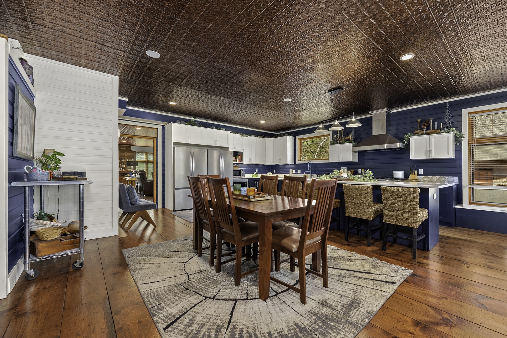 Gather around this stunning dining and kitchen space, where rich wood floors meet striking navy walls and a statement tin ceiling—perfect for your family meals and memorable celebrations together.
